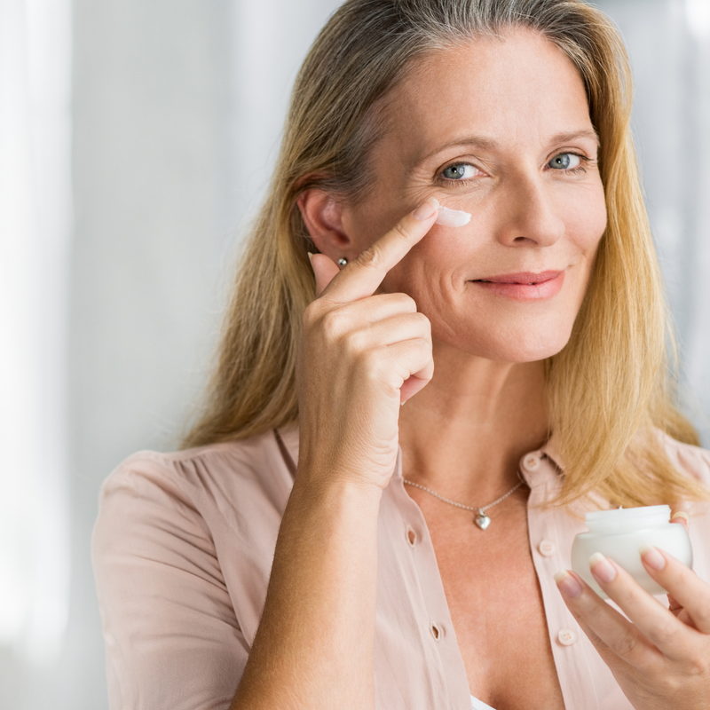 Woman applying moisturizer to mature skin